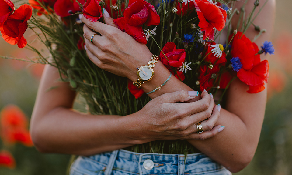 czerwone kwiaty i zegarek założony na rękę